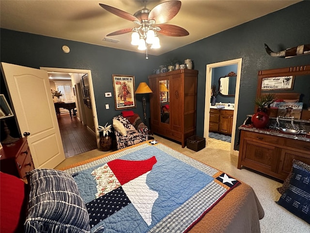 carpeted bedroom with ensuite bath and ceiling fan