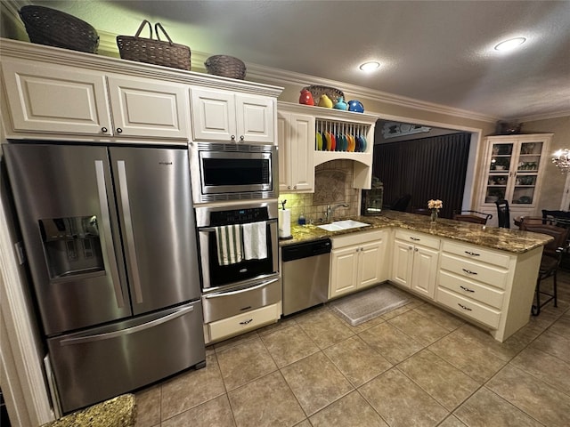 kitchen with kitchen peninsula, appliances with stainless steel finishes, light tile floors, dark stone counters, and tasteful backsplash