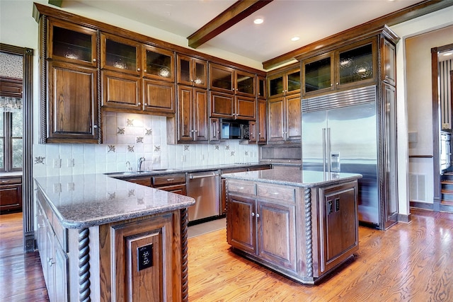 kitchen with stone counters, appliances with stainless steel finishes, a center island, and light wood-type flooring