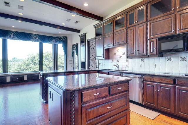 kitchen featuring black appliances, a kitchen island, decorative backsplash, dark stone counters, and beamed ceiling