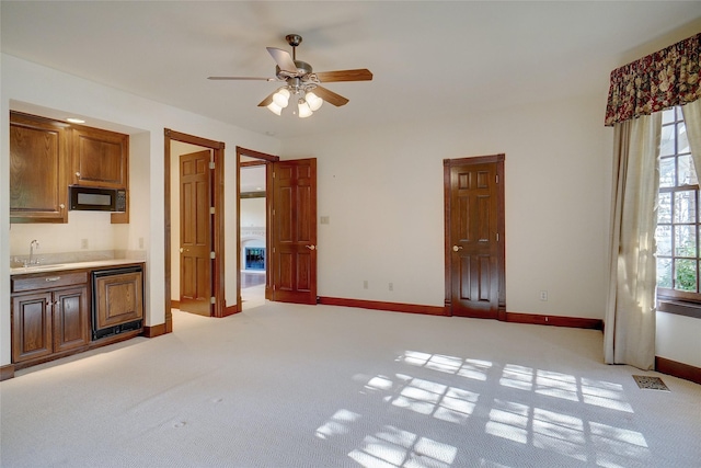 interior space featuring sink, light colored carpet, a healthy amount of sunlight, and ceiling fan