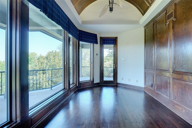 interior space with a raised ceiling, dark wood-type flooring, and ceiling fan