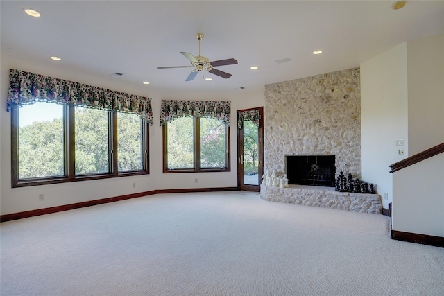 unfurnished living room with ceiling fan, a fireplace, carpet, and a wealth of natural light