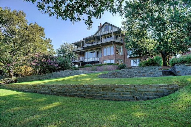 rear view of property with a balcony and a yard