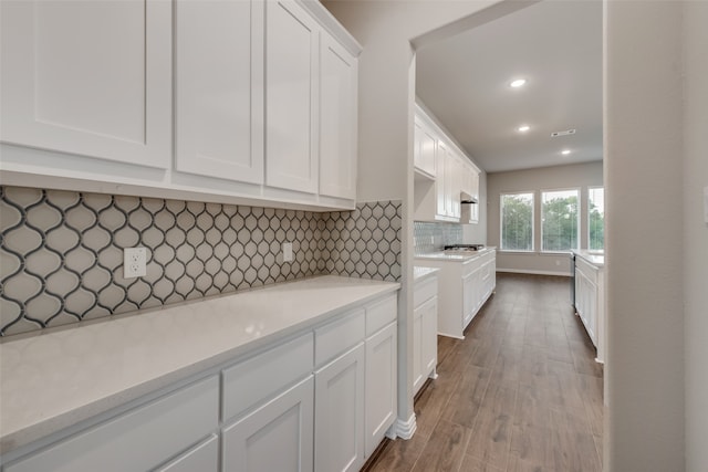 kitchen featuring white cabinets, hardwood / wood-style flooring, and tasteful backsplash