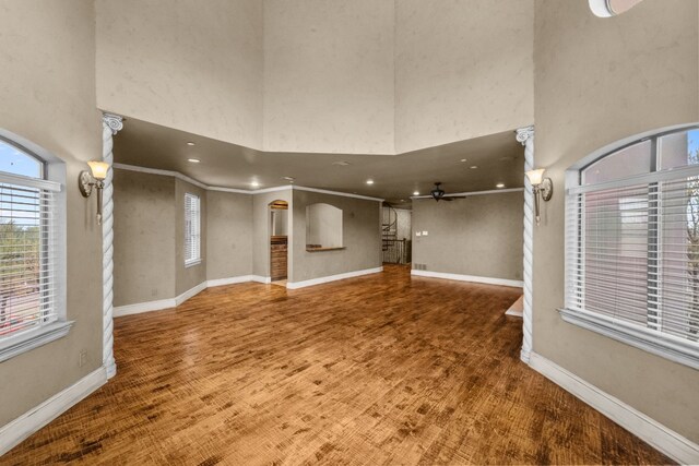 interior space with crown molding, dark hardwood / wood-style floors, ceiling fan, and a high ceiling