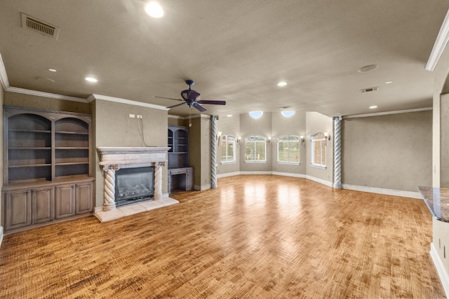 unfurnished living room with built in shelves, ornamental molding, ceiling fan, and light wood-type flooring