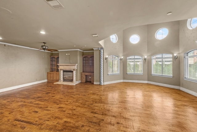 unfurnished living room featuring a healthy amount of sunlight, hardwood / wood-style floors, ceiling fan, and a towering ceiling