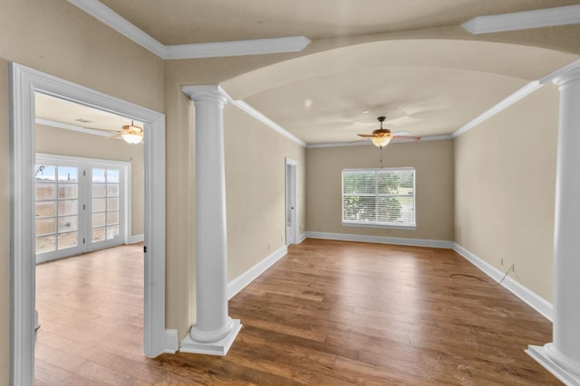 empty room with french doors, ceiling fan, crown molding, light hardwood / wood-style flooring, and ornate columns