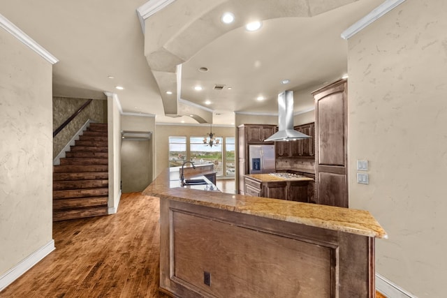 kitchen with sink, a kitchen island, dark hardwood / wood-style flooring, island range hood, and stainless steel refrigerator with ice dispenser