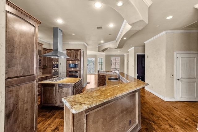 kitchen with light stone countertops, ornamental molding, a large island, island exhaust hood, and dark hardwood / wood-style floors