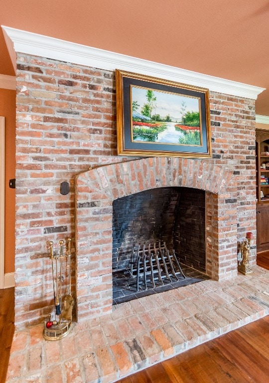 room details with a brick fireplace, ornamental molding, and wood-type flooring