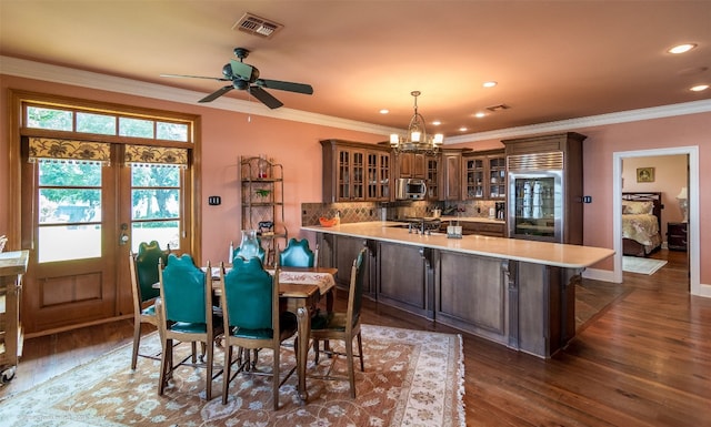 interior space with ceiling fan with notable chandelier, tasteful backsplash, dark wood-type flooring, crown molding, and hanging light fixtures