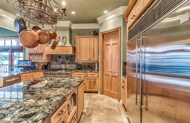 kitchen featuring dark stone countertops, crown molding, tasteful backsplash, and high end appliances