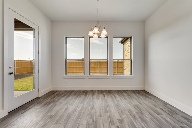 unfurnished dining area with light wood-type flooring and a notable chandelier