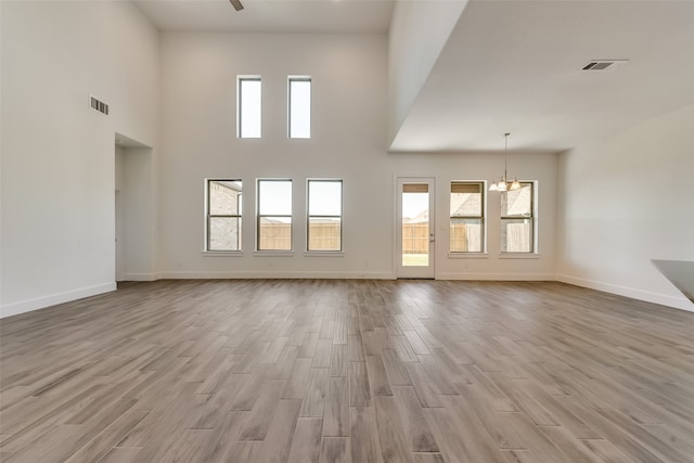 unfurnished living room with a high ceiling and an inviting chandelier