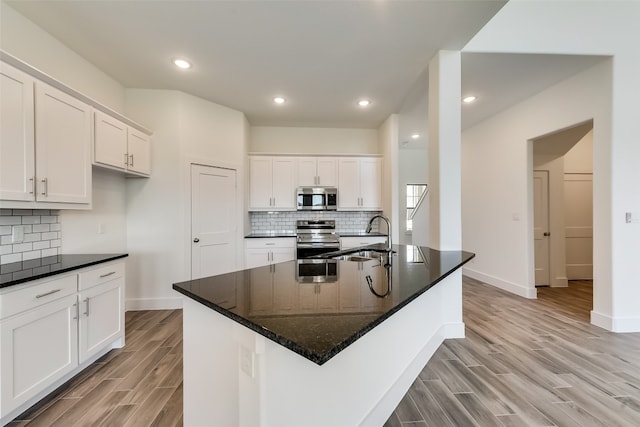 kitchen with white cabinets, appliances with stainless steel finishes, a kitchen island with sink, and sink