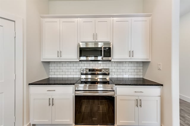 kitchen featuring white cabinets, dark stone countertops, stainless steel appliances, and hardwood / wood-style flooring