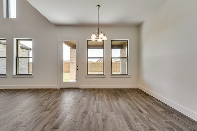 unfurnished dining area with hardwood / wood-style flooring and an inviting chandelier