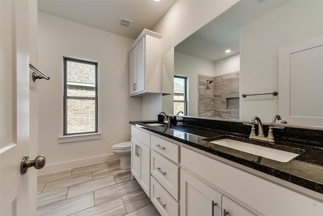 bathroom with tiled shower, vanity, and toilet