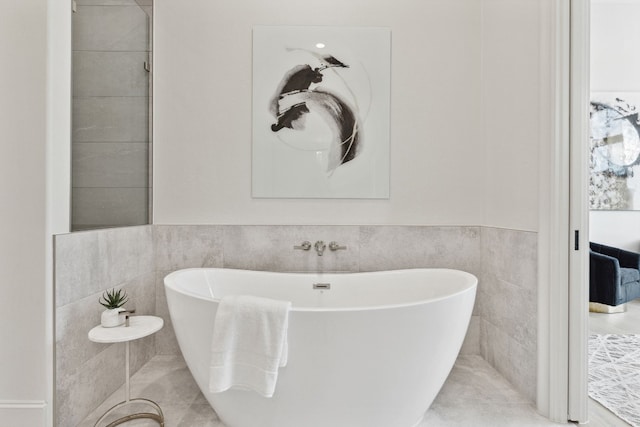 bathroom with tile walls, tile flooring, and a washtub