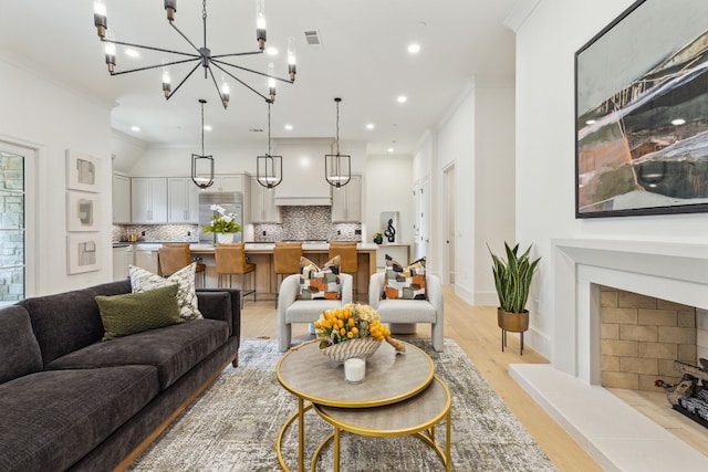 living room featuring a chandelier, ornamental molding, and light wood-type flooring