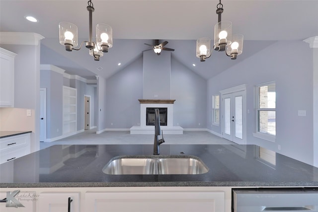 kitchen with high vaulted ceiling, white cabinets, ceiling fan with notable chandelier, pendant lighting, and sink