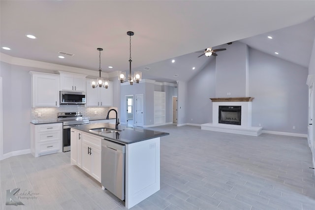 kitchen with sink, lofted ceiling, white cabinetry, hanging light fixtures, and stainless steel appliances