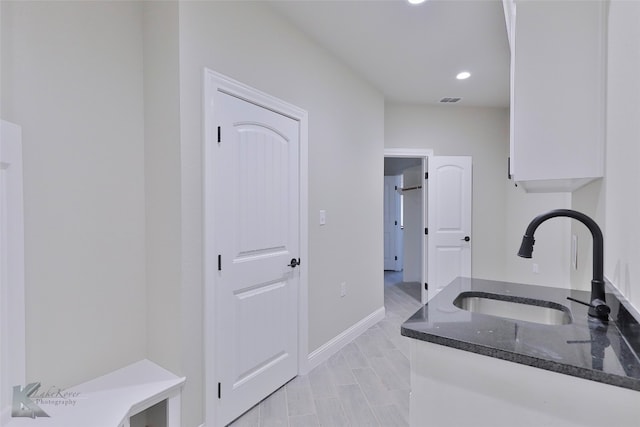 kitchen with dark stone countertops, sink, and white cabinetry