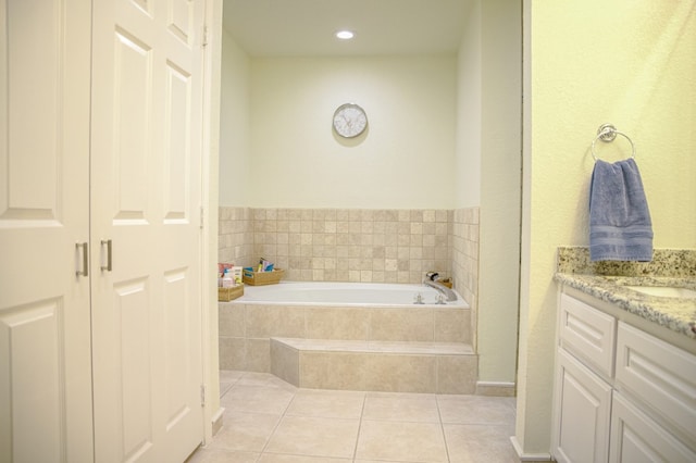 bathroom with tiled tub, vanity, and tile flooring