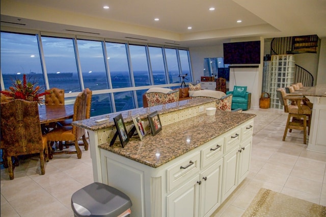 kitchen featuring a water view, stone countertops, a kitchen island, and light tile floors