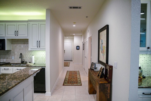 interior space featuring white cabinets, tasteful backsplash, dark stone countertops, and sink