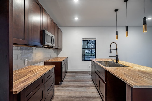 kitchen with butcher block countertops, tasteful backsplash, light hardwood / wood-style floors, and pendant lighting