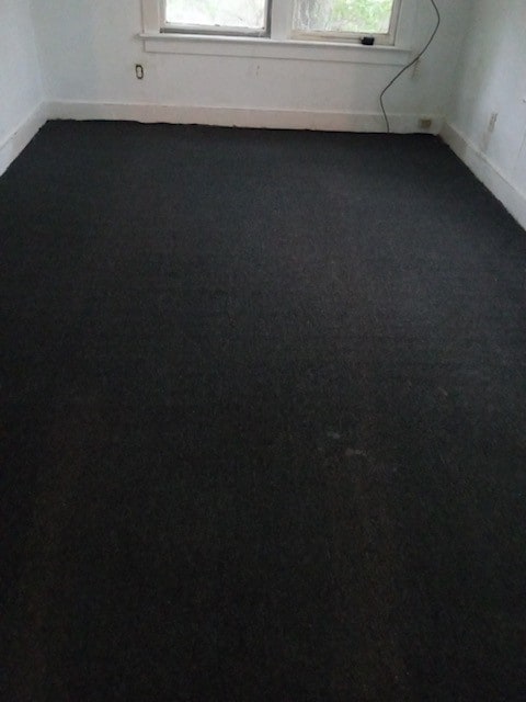 unfurnished room featuring dark colored carpet