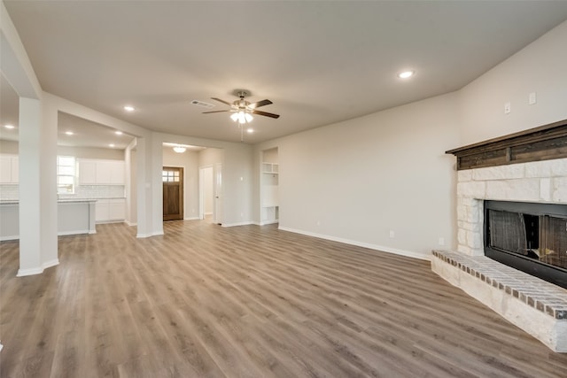 unfurnished living room with ceiling fan, light hardwood / wood-style flooring, and a fireplace