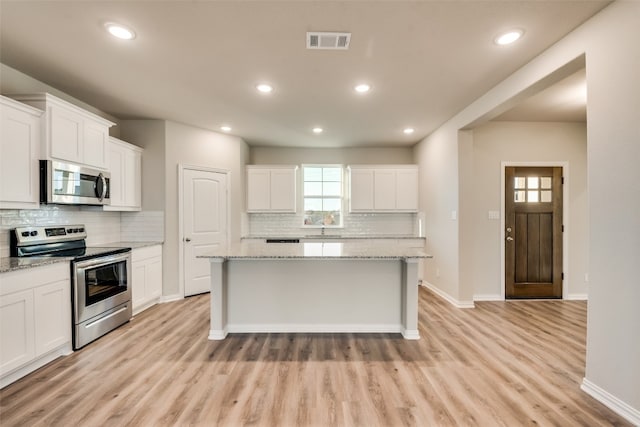 kitchen featuring white cabinetry, appliances with stainless steel finishes, a kitchen island, and light hardwood / wood-style floors