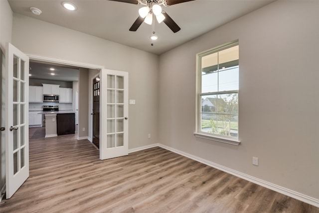 unfurnished room with ceiling fan, light wood-type flooring, and french doors