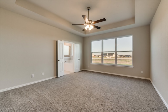 spare room featuring ceiling fan, light colored carpet, and a tray ceiling