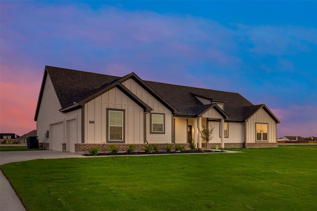 view of front of house with central air condition unit, a yard, and a garage