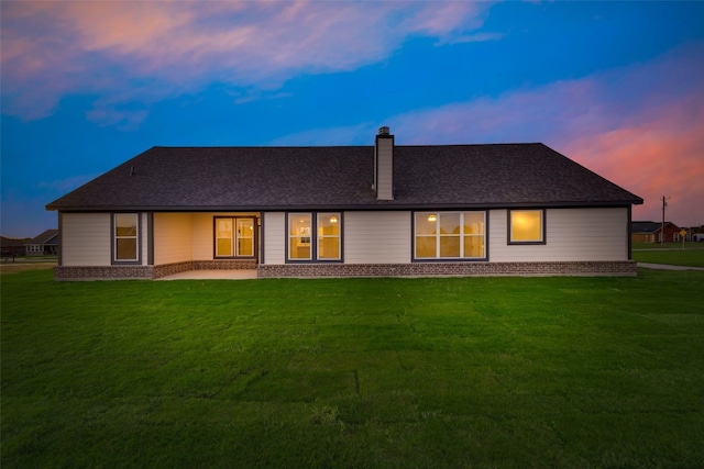 back house at dusk featuring a yard