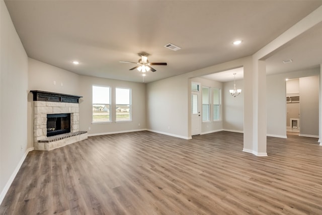 unfurnished living room with a fireplace, ceiling fan with notable chandelier, and dark wood-type flooring