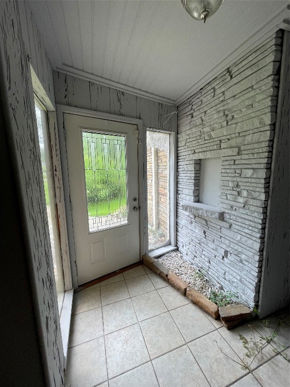 doorway featuring wood walls and light tile floors