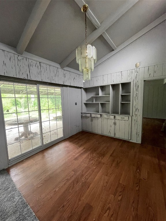 unfurnished living room with a chandelier, dark wood-type flooring, and lofted ceiling with beams