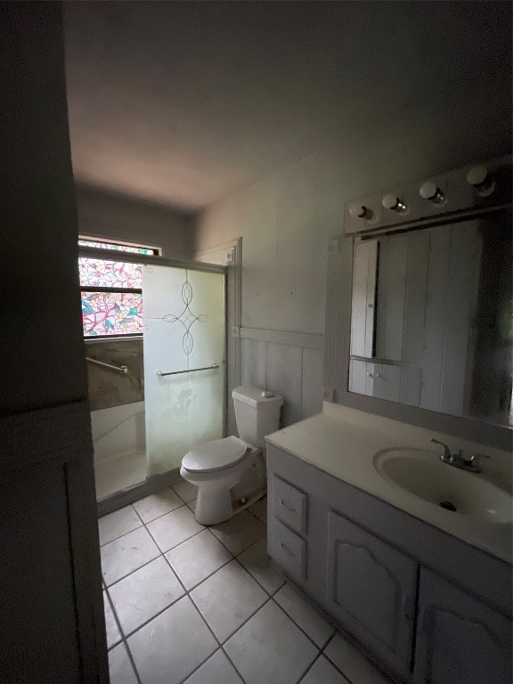 bathroom featuring tile floors, toilet, vanity, and an enclosed shower