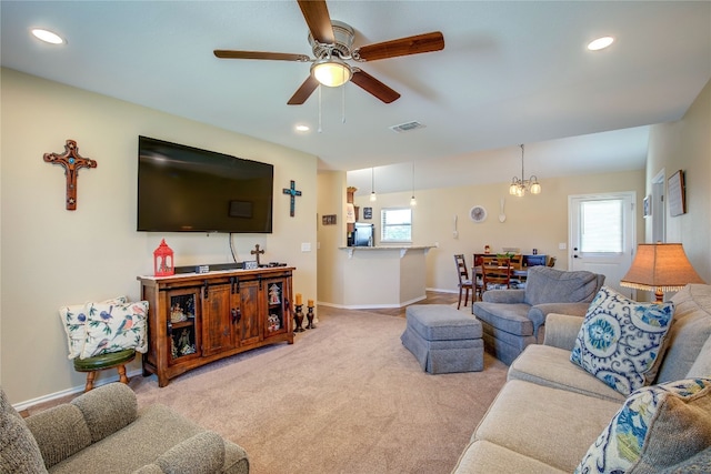 carpeted living room featuring ceiling fan with notable chandelier