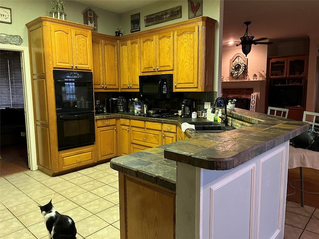 kitchen with black appliances, light tile patterned flooring, kitchen peninsula, and sink