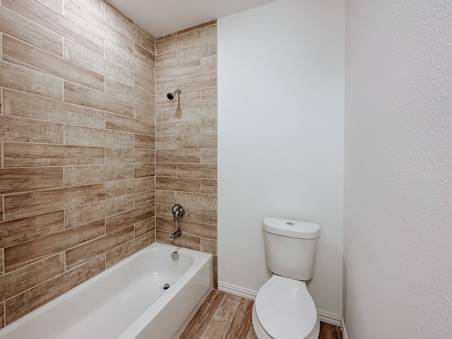 bathroom featuring hardwood / wood-style flooring, toilet, and tiled shower / bath