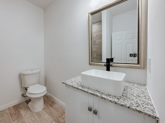 bathroom with toilet, vanity, and hardwood / wood-style floors