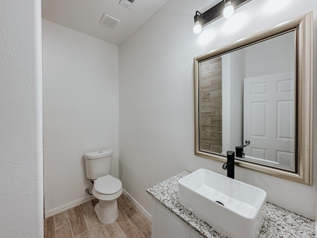 bathroom featuring toilet, vanity, and hardwood / wood-style floors