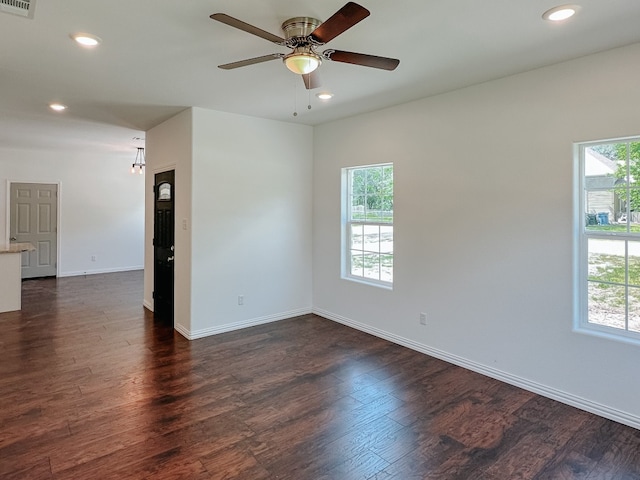 spare room featuring dark hardwood / wood-style floors, ceiling fan, and a wealth of natural light